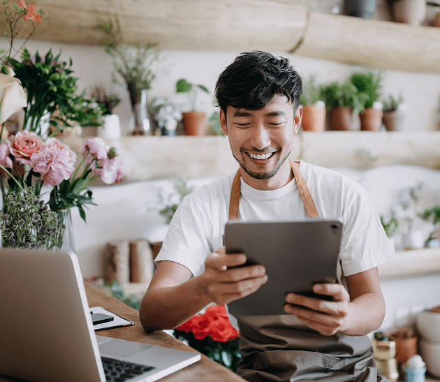 Smiling florist holding tablet at work